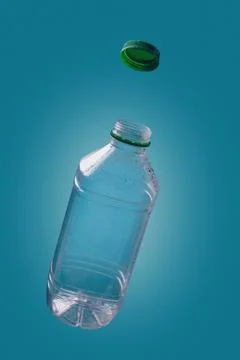Empty plastic bottle with water drops and green cover levitating Stock Photos