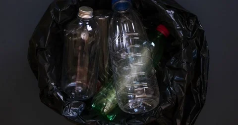 Empty plastic bottles fall into the trash can with a black plastic bag Stock Footage 235585386