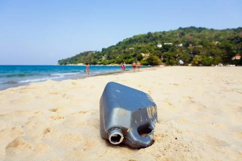 An empty plastic canister is lying on the sand of the resort beach. Stock Photos