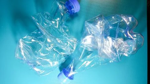 Empty plastic crushed water bottles on blue background. Environmental plastic Stock Photos