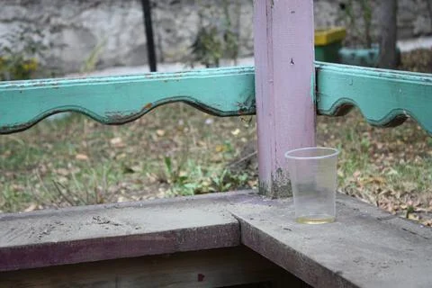 Empty plastic cup left on an old abandoned wooden arbor porch Stock Photos