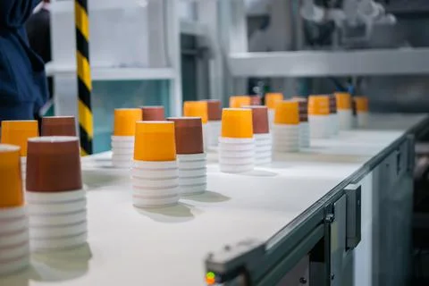 Empty plastic cups moving on conveyor belt at package exhibition Stock Photos