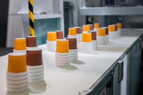 Empty plastic cups moving on conveyor belt at package exhibition Stock Photos