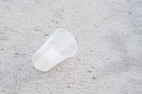 Empty plastic disposable glass on beach, environmental pollution Stock Photos