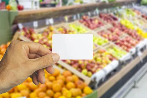 Empty plastic grocery card in hand on supermarket background. Grocery card for Stock Photos