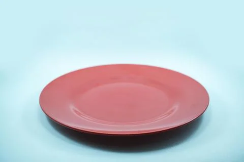 Empty plastic red plate isolated on turquoise background. Stock Photos