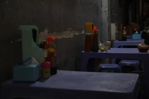 Empty plastic tables and chairs set up in a dimly lit alleyway Stock Photos