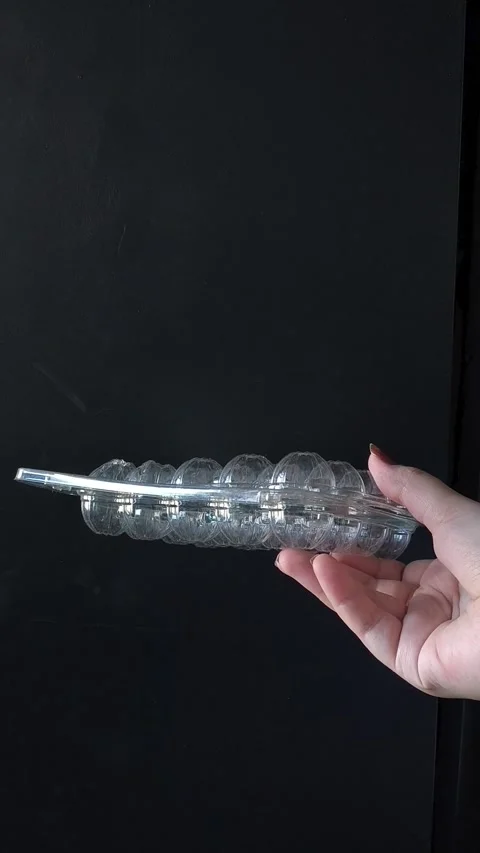 Empty plastic transparent tray for quail eggs in hand on black background Video stock 332409945