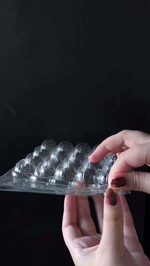 Empty plastic transparent tray for quail eggs in hand on black background Stockbeeldmateriaal 332409965