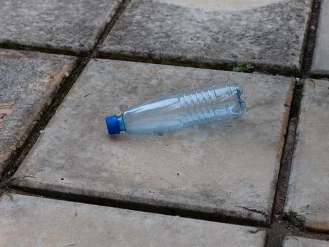 Empty plastic water bottle on stone pavement Stock Photos