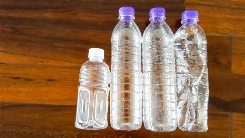 Empty plastic water bottles placed on a blurred reddish brown wooden floor,.. Stock Photos