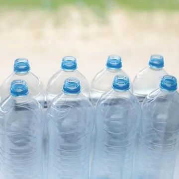 Empty plastic water bottles on table - recycling and food storage concept Stock Photos