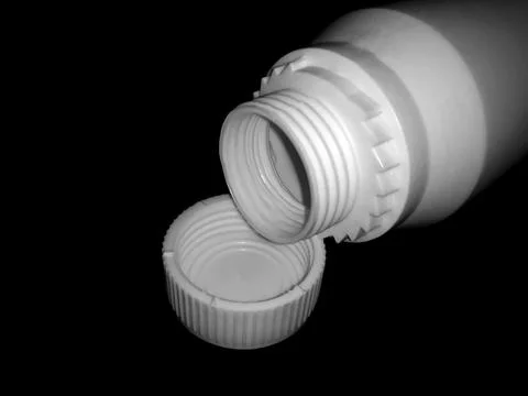 The empty plastic white bottle is on a dark background. Stock Photos
