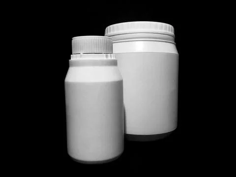 Empty plastic white bottles on a dark background. Stock Photos