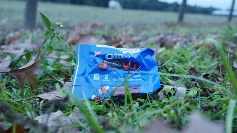 Empty plastic wrapping package of Oreo cookies left as waste on a grassy field. Foto stock