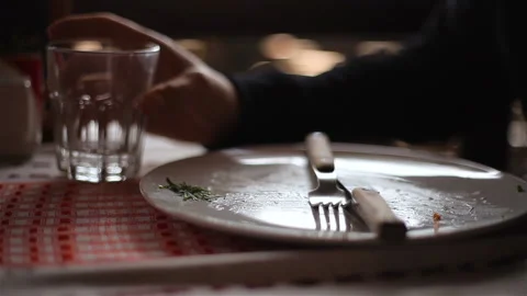 An empty plate after eating A hand takes a glass of water Stockbeeldmateriaal 150277212