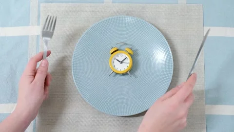 Empty plate with alarm clock and female hand against the background of blue Stock Footage 263938220