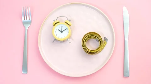 Empty plate with alarm clock and measuring tape on pink background. Stock Footage 288183325