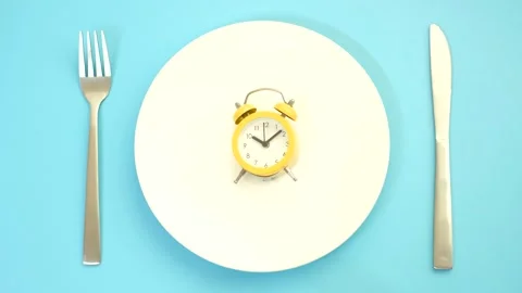 Empty plate with alarm clock on blue background, intermittent fasting concept. Stock Footage 288288825