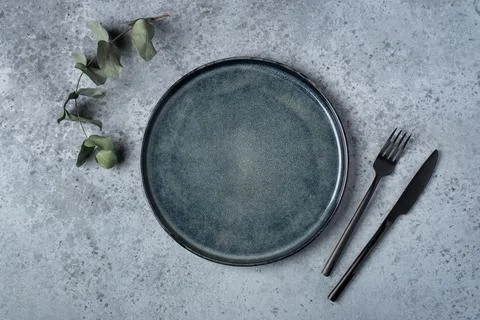 An empty plate and cutlery on a gray table. Stock Photos