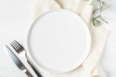 An empty plate and cutlery on a white table. Stock Photos