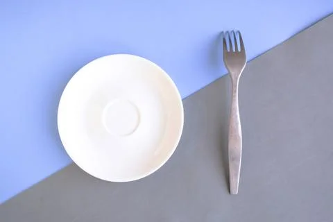 Empty plate and fork on grey and blue background. Copy space for the text. Mi Stock Photos