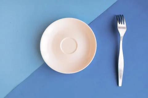 Empty plate and fork on grey and blue background. Copy space for the text. Mi Foto stock