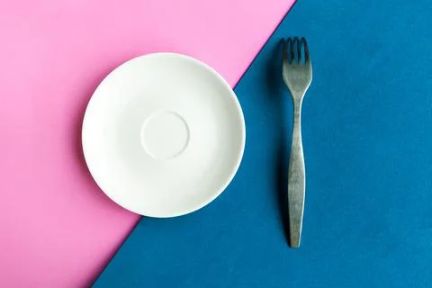 Empty plate and fork on pink and blue background. Copy space for the text. Mi Stock Photos