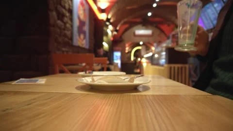 Empty plate and used spoon rest on wooden table of cafe with person placing Stock Footage 335762510
