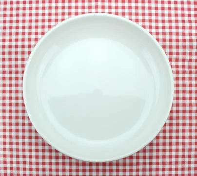 Empty plate on checkered tablecloth Stock Photos