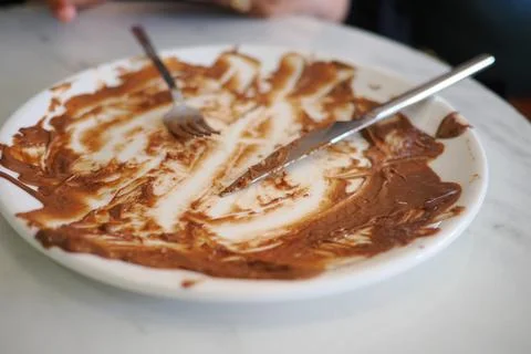 Empty plate with chocolate spread, utensils resting after dessert Stock Photos