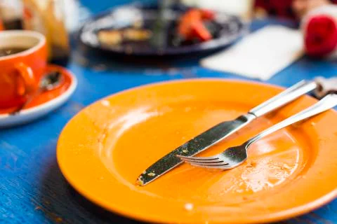 Empty plate with cutlery after a meal on a table Stock Photos