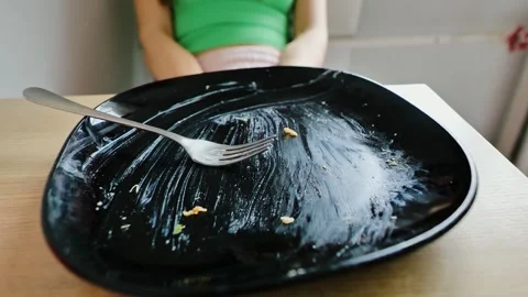 Empty Plate in Focus While Woman Holds Stomach – Overeating Consequences Concept Stock Footage 321717398