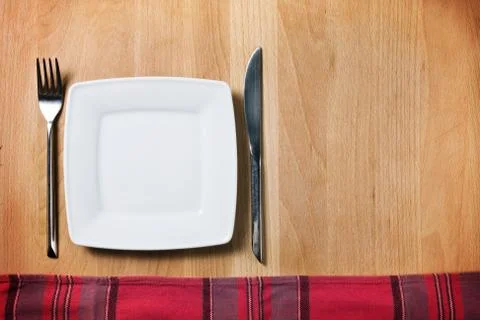 Empty plate with fork and knife on wooden table, table arrangement Stock Photos