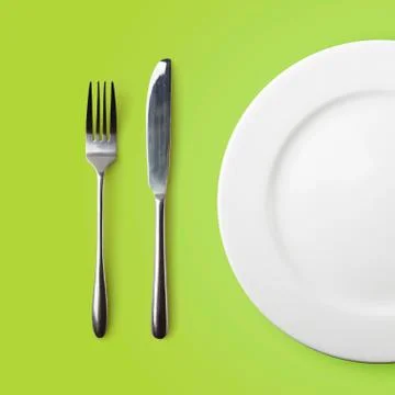 Empty plate, fork and knife on green background Stock-Fotos