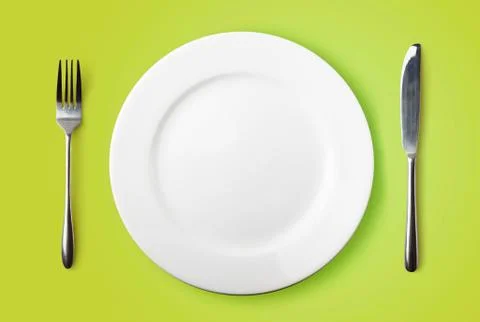 Empty plate, fork and knife on green background Foto stock