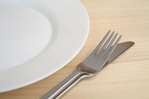 Empty plate with fork and knife on the wooden table Stock Photos