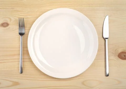 Empty plate with fork and knife on the wooden table Stock Photos