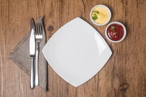 Empty plate with fork and knife, ketchup and mayonnaise Foto stock