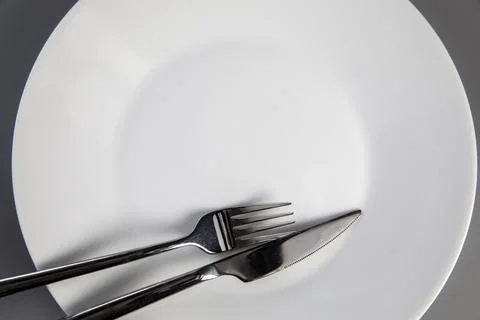 Empty plate with fork and knife on gray background, top view for copy space Stock Photos