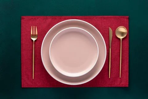Empty plate with fork and knife on dark green table. Festive place setting .. Stock Photos