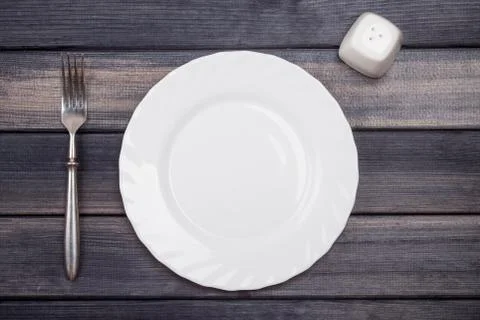 Empty plate, fork and salt shaker on wooden table, top view Stock Photos