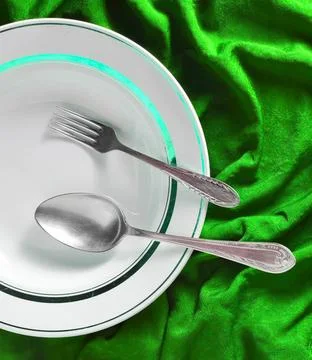 Empty plate with fork and spoon on green fabric background 스톡 사진