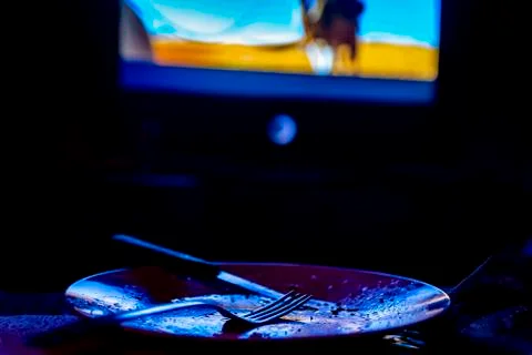 Empty plate in front of tv - lonely night Stock Photos