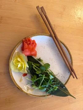 Empty plate with ginger, microgreens, flower, chopsticks on wood table concep 스톡 사진