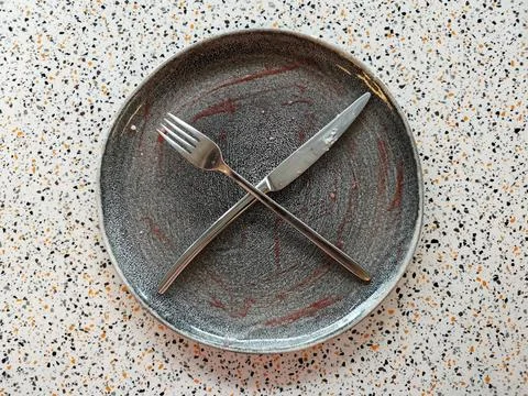 An empty plate left after dessert, a knife and a fork crossed Stock Photos