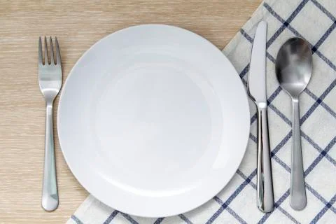 Empty plate with napkin and silverware Stock Photos
