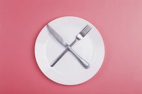 Empty plate on a pink minimal background. Empty white ceramic plate with knife Foto stock