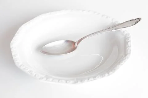 Empty plate with silver spoon isolated on white Stock Photos