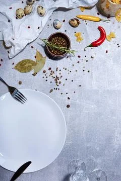 Empty plate with spices and vegetables on white table Stock Photos